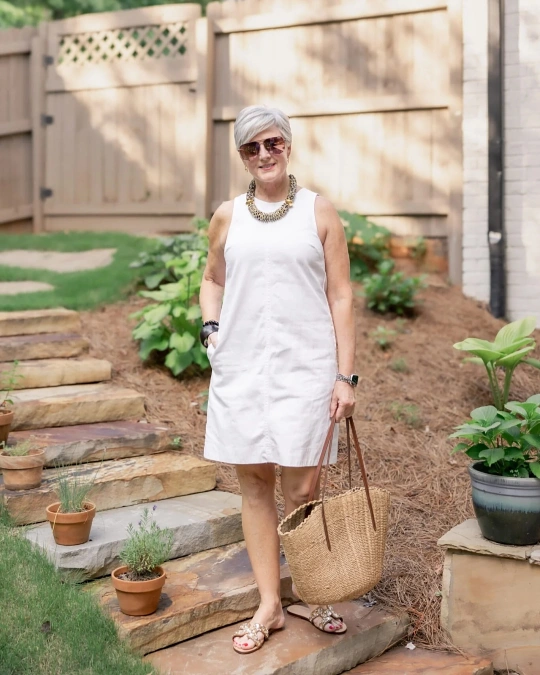White shift dress with straw tote stylish outfit for women over 50