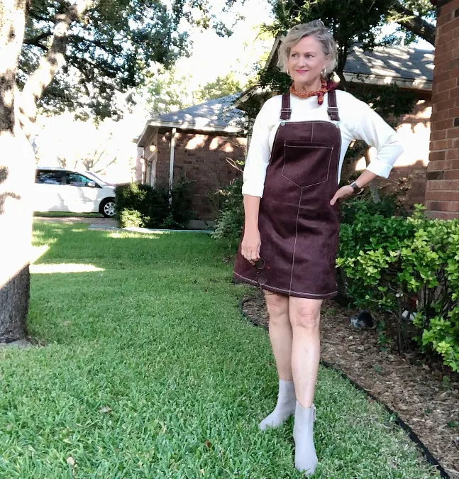 Burgundy suede pinafore dress layered over white top outfit for women over 50