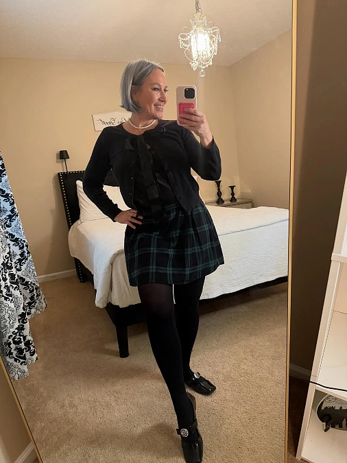 Tartan mini skirt and black cardigan Christmas outfit for women over 50