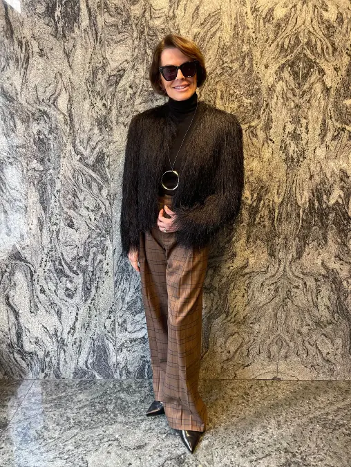 Black textured jacket and brown plaid trousers holiday outfit for women over 50